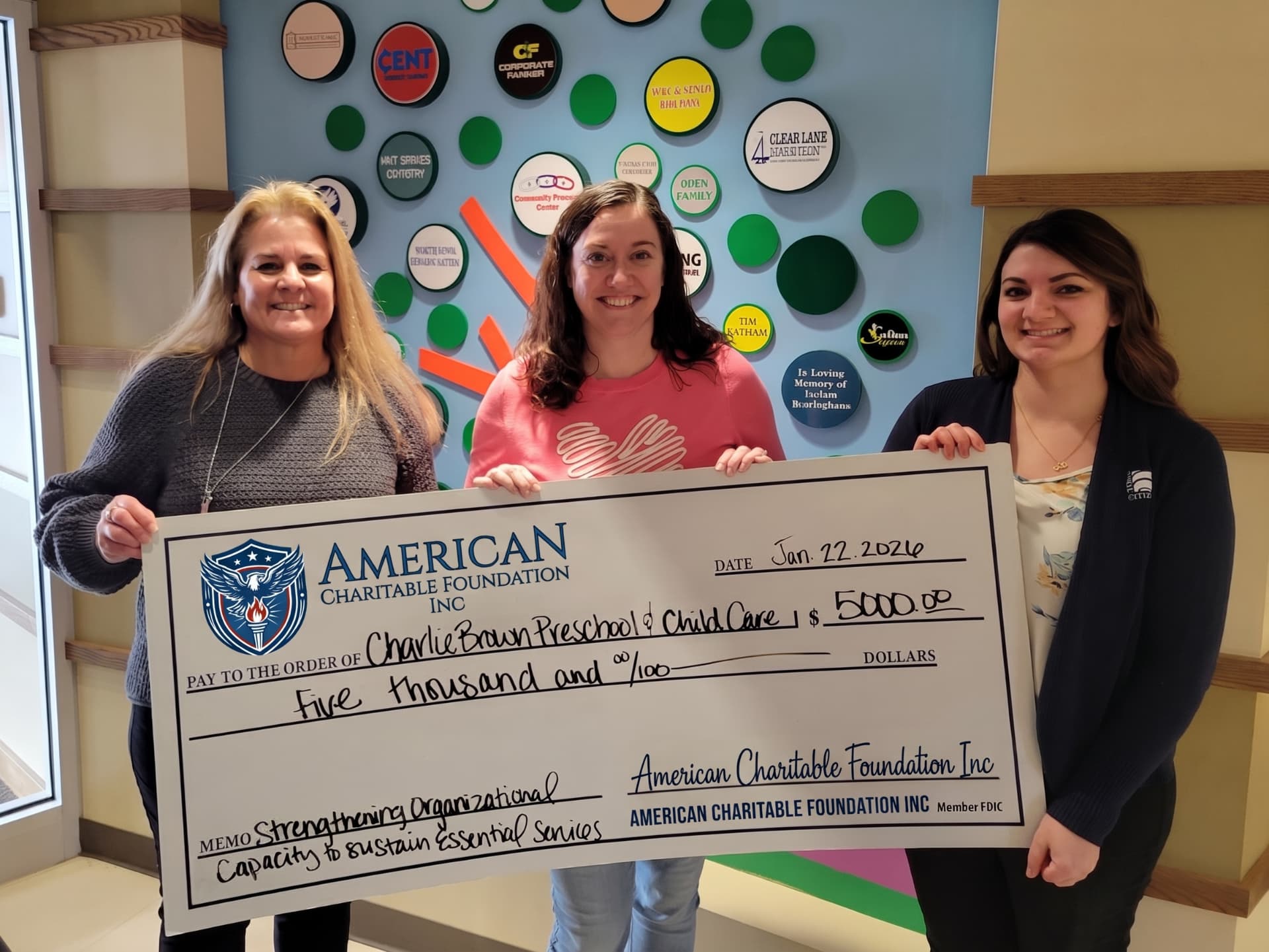 Three women presenting a large ACF grant check at Charlie Brown Preschool & Child Care