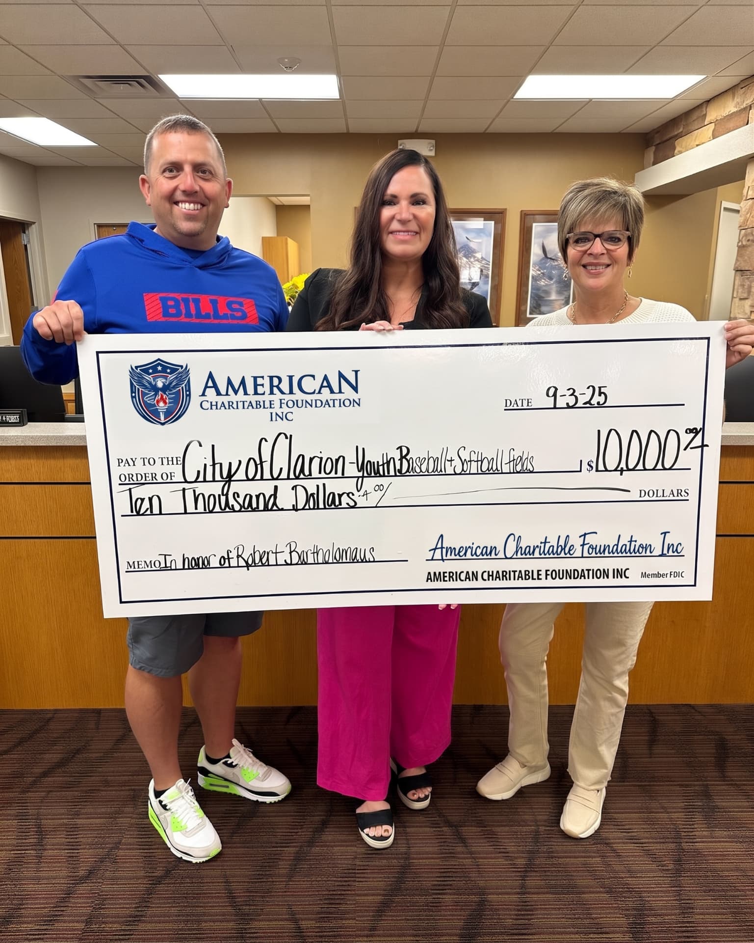 Three people presenting a large ACF grant check for City of Clarion youth baseball and softball fields in an office lobby