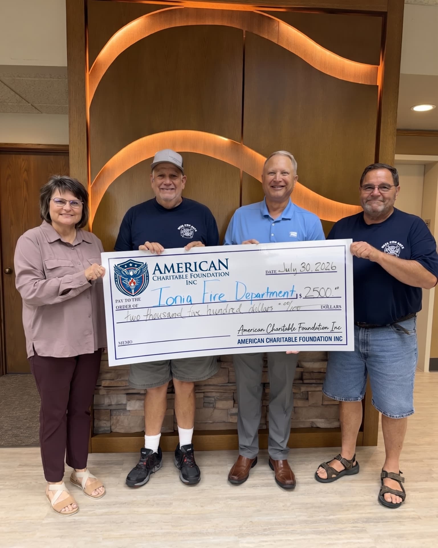 Four people presenting a large ACF grant check for the Ionia Fire Department